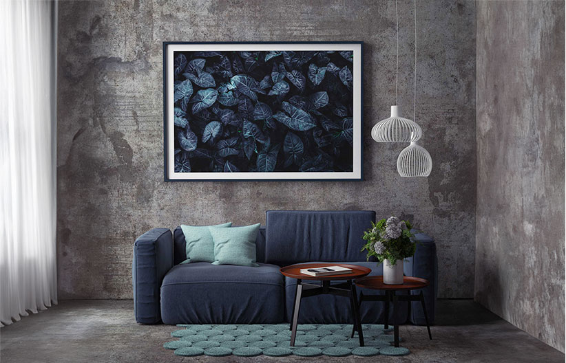 Mockup of a picture on a grey wall with a sofa, table and lights infront.